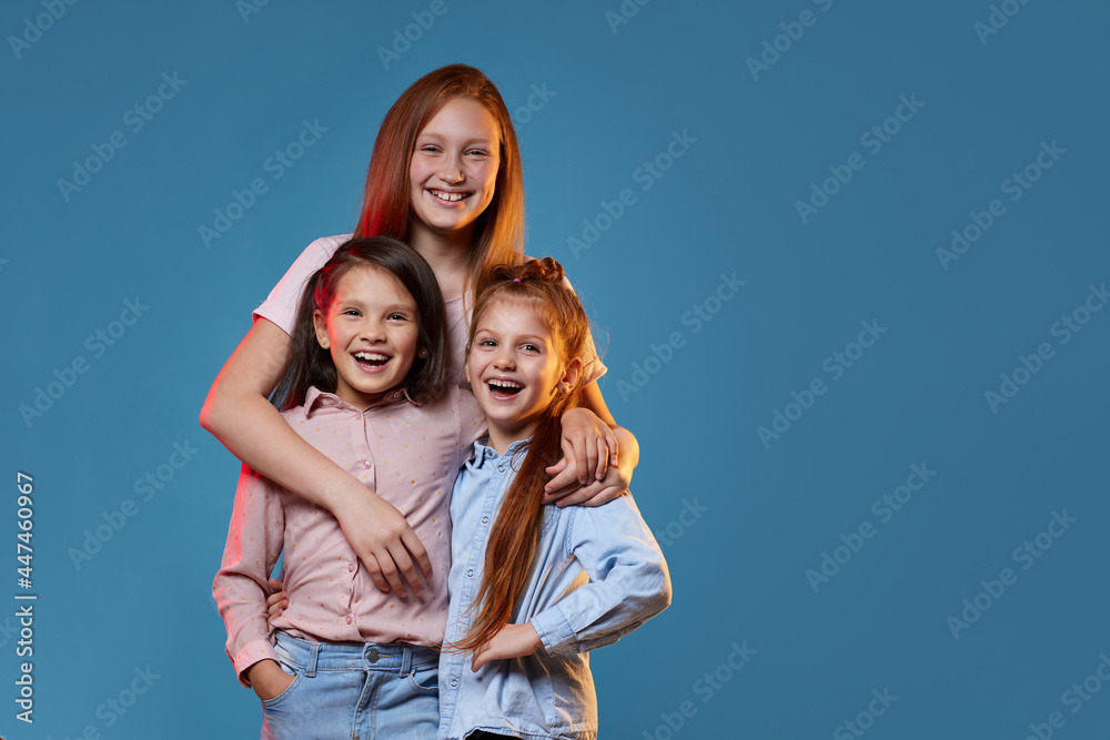 three kids girls standing together on blue background three kids girls standing together on blue background