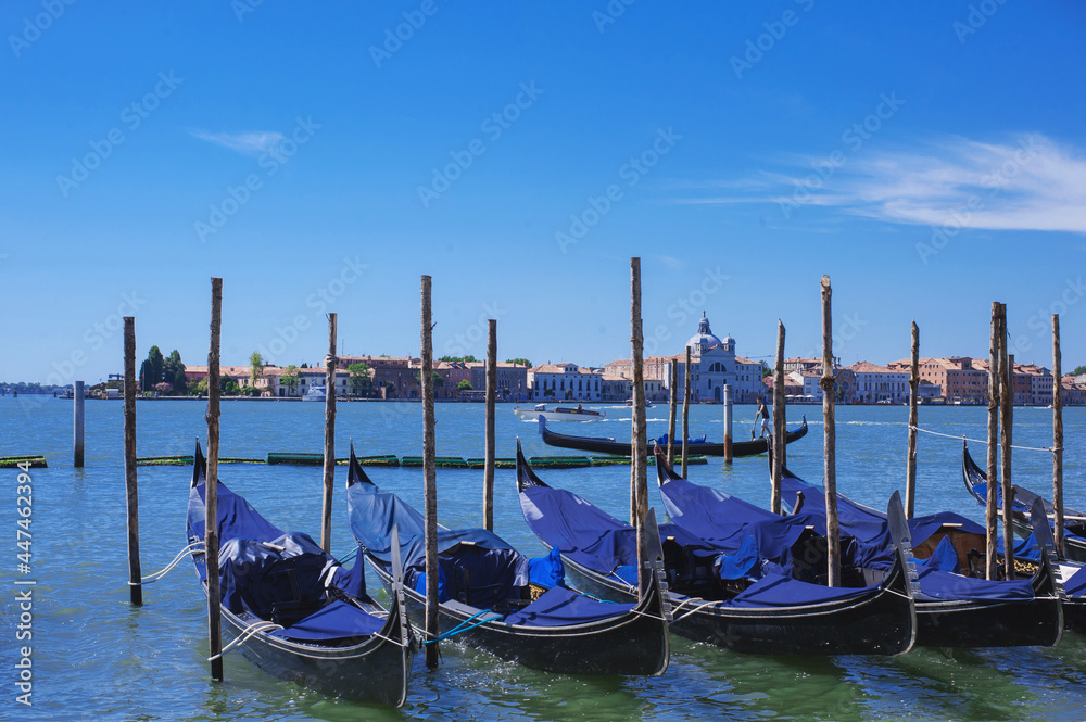moored gondolas on a peir to in blue clean waters of busy grand canal of Venice