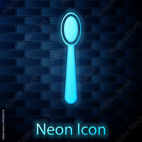 Glowing neon Disposable plastic spoon icon isolated on brick wall background. Vector Illustration
