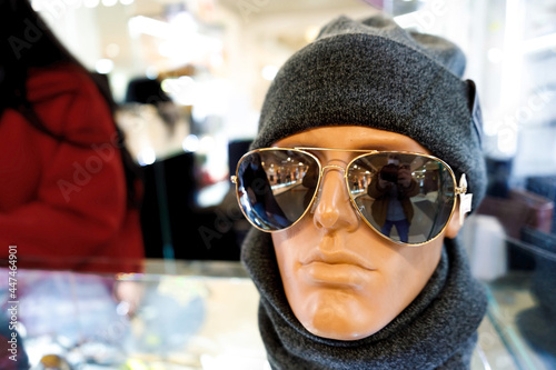 White mannequin dummy head with set dark grey hat and scarf and black glasses in store or mall showcase