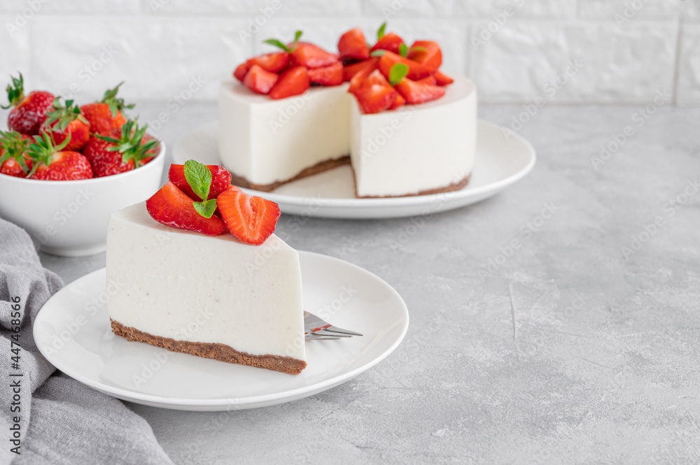 No baked cheesecake with fresh strawberries and mint on top on a white plate on a gray concrete background. Copy space. No baked cheesecake with fresh strawberries and mint on top on a white plate on a gray concrete background. Copy space.
