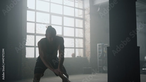 Athlete using hammer during fitness workout. Fitness man beating rubber tire 