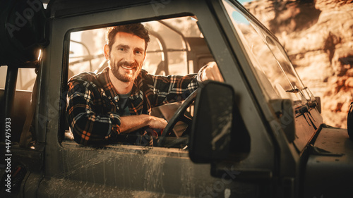 Desert Road Trip: Portrait of Handsome Male Explorer Looking out of Car Driver Window and Smiling. Adventurer Traveling through the Canyon on His Offroad SUV. Vacation Journey Through Marvelous Nature