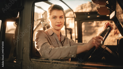 Desert Road Trip: Portrait of Beautiful Female Explorer Looking out of Car Driver Window and Smiling. Woman Adventurer Traveling through the Canyon on Her Offroad SUV. Journey Through Marvelous Nature