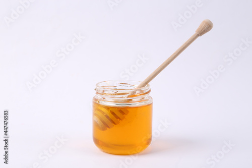 Bee honey jar and honey wooden spoon on white background