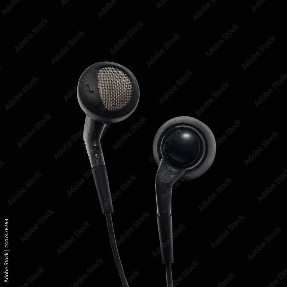 Black headphones for mobile devices on a black background. Black headphones for mobile devices on a black background.