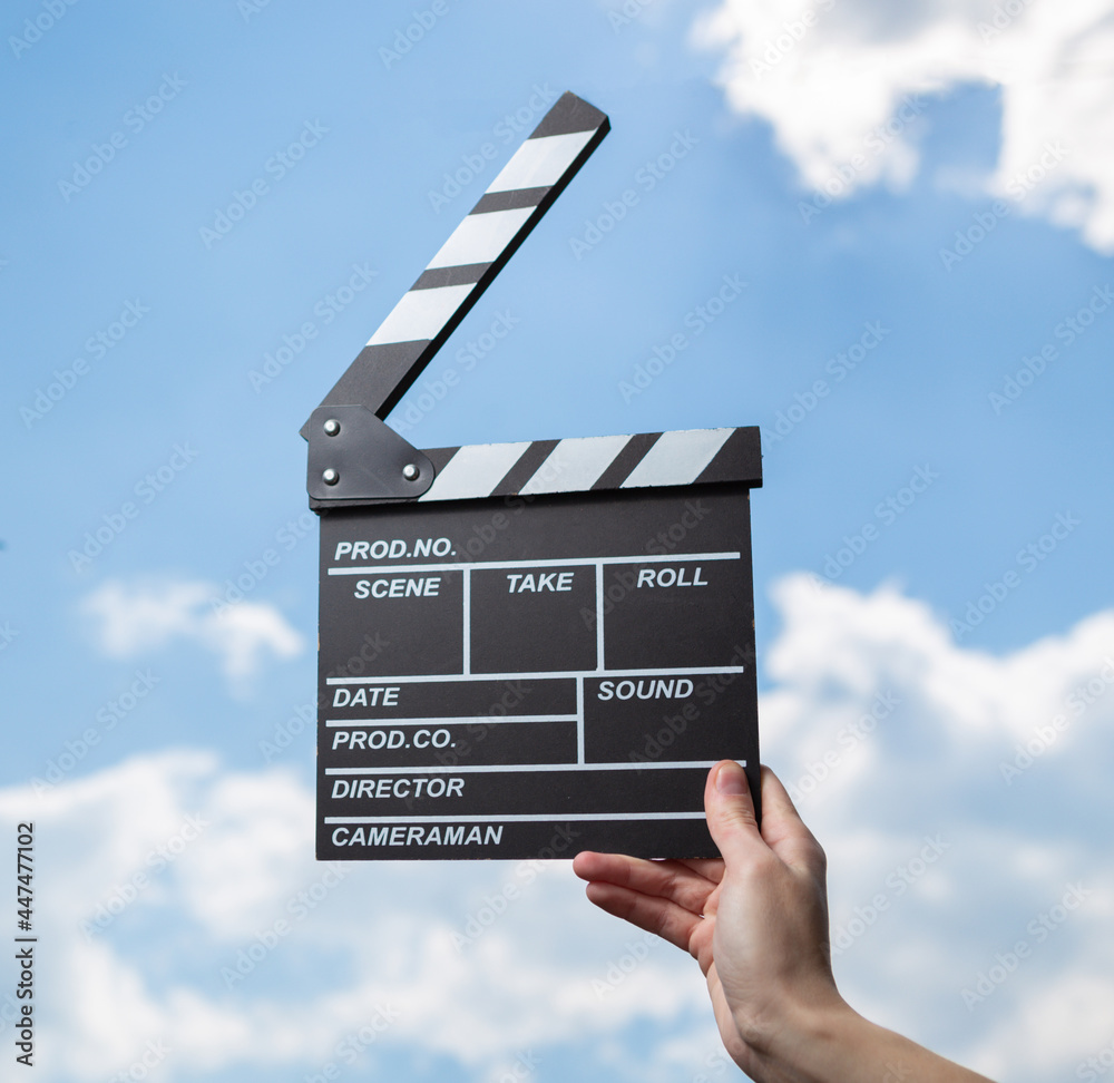 Εκτύπωση καμβά Hand holds movie board on background of blue sky with clouds.