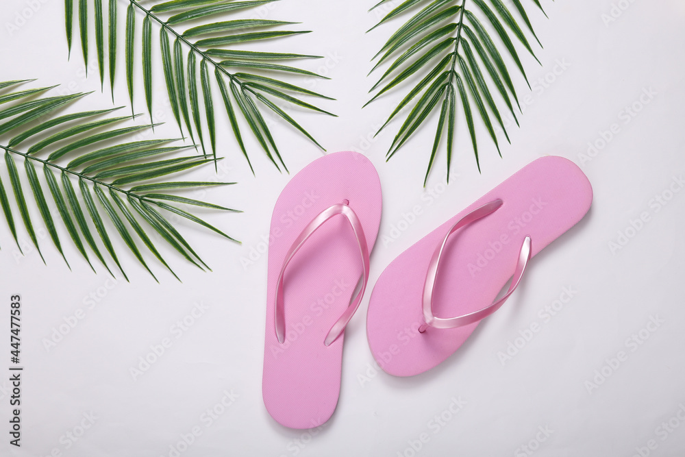 Flip-flops and palm green leaves on white background. Travel concept. Tropical composition. Top view. Flat lay Flip-flops and palm green leaves on white background. Travel concept. Tropical composition. Top view. Flat lay