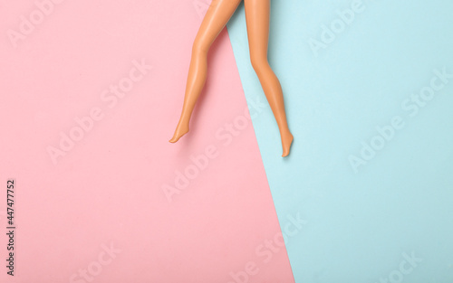 Doll female bare feet on a blue-pink pastel background. Creative minimalistic layout