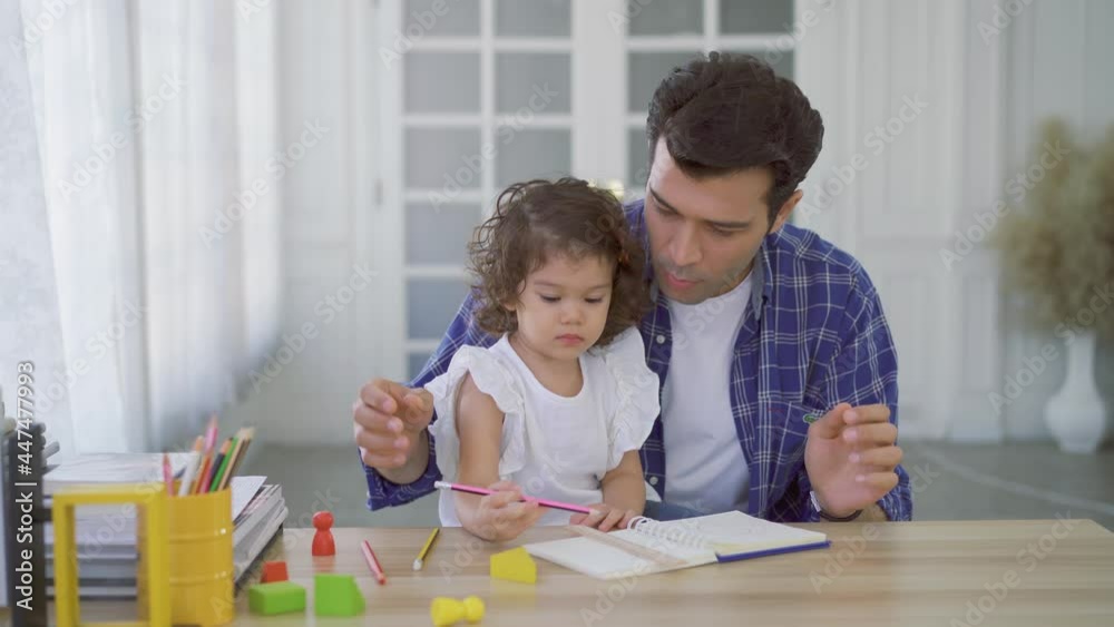 Young father teaching his cute little daughters' study. Excited smiling small child girl enjoying learning with pleasant dad at home. Children education, home schooling concept Young father teaching his cute little daughters' study. Excited smiling small child girl enjoying learning with pleasant dad at home. Children education, home schooling concept