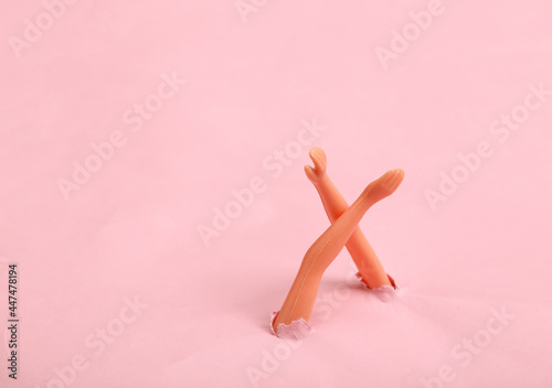 Doll hands through the torn hole of pink paper. Minimalism, concept art photo