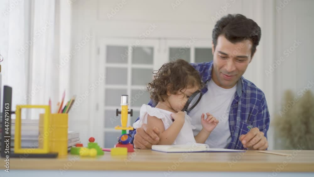Little girl doing science experiments in the laboratory with father who looks through magnifying glass. Dad and daughter study biology and chemistry lessons with microscope. Homeschooling Little girl doing science experiments in the laboratory with father who looks through magnifying glass. Dad and daughter study biology and chemistry lessons with microscope. Homeschooling