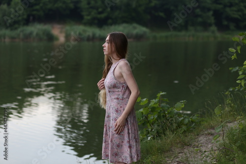 Long haired woman in pink dress standing near water