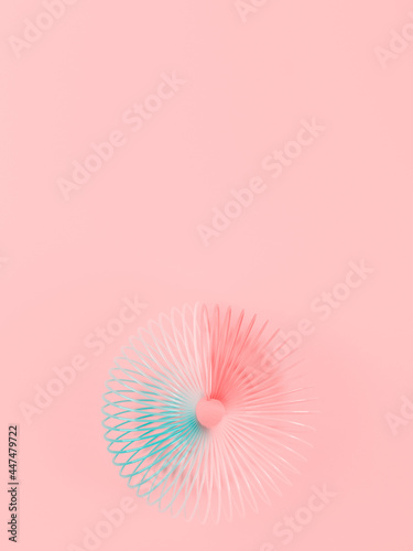 Colorful rainbow spiral plastic toy on pink background