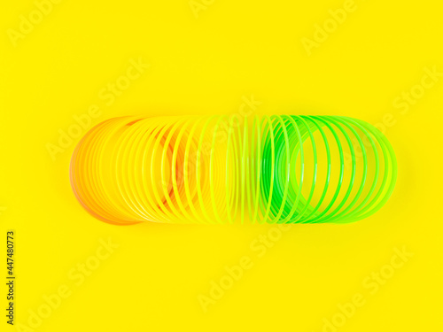 Colorful rainbow spiral plastic toy on yellow background photo