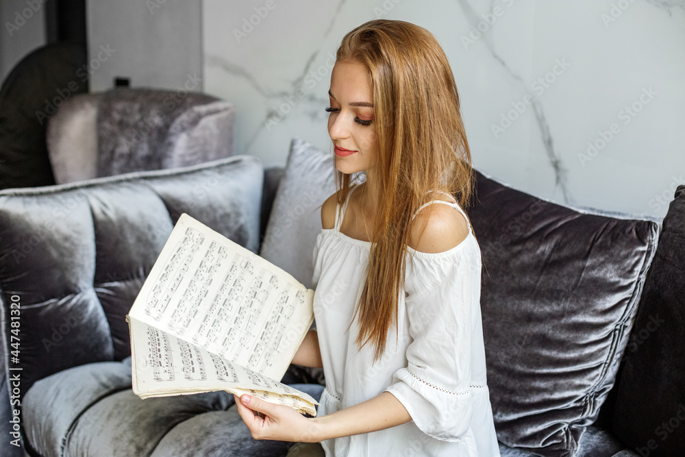 A girl holds sheets of music, a romantic actress with long hair A girl holds sheets of music, a romantic actress with long hair
