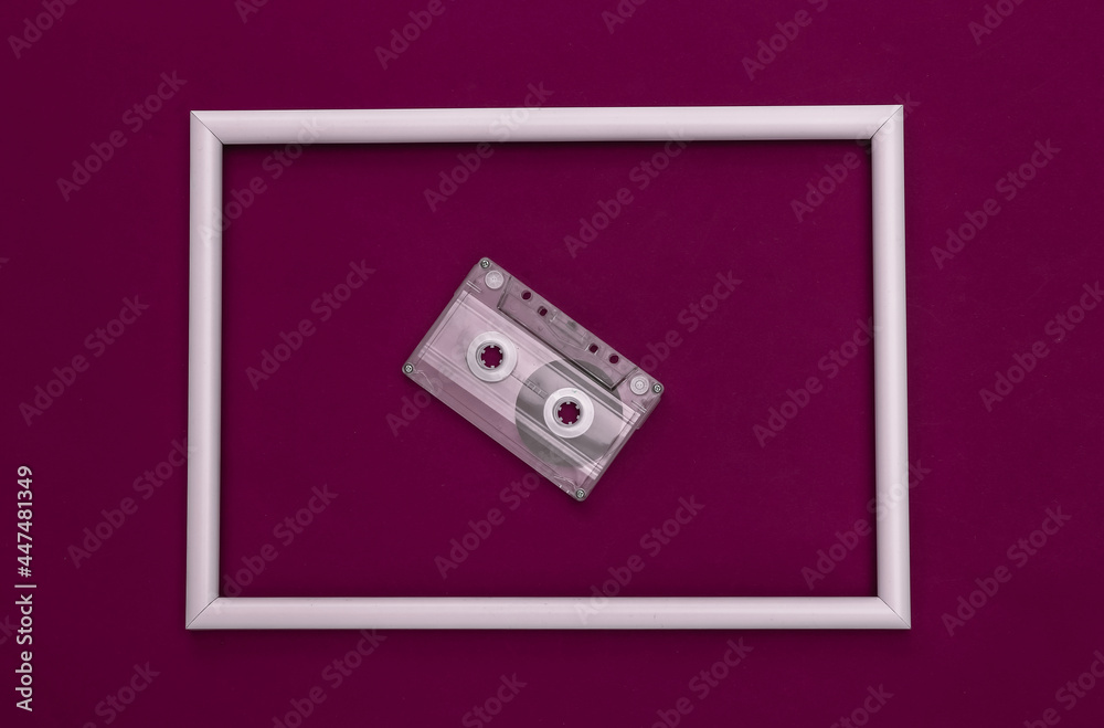 Fototapeta premium Retro audio cassette on purple background with white frame. Top view