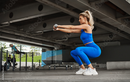 Attractive fitness woman doing squats with dumbbells © kiuikson