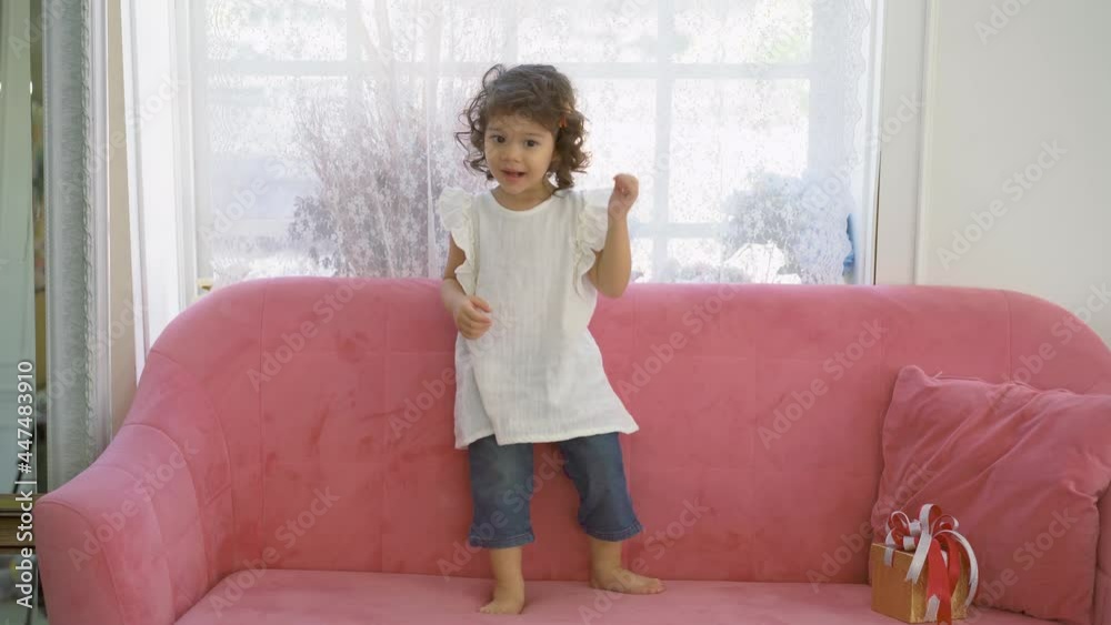 Cute little kid daughter jumping dancing in modern house living room, Child girl having fun enjoy playing funny activity together at home Cute little kid daughter jumping dancing in modern house living room, Child girl having fun enjoy playing funny activity together at home