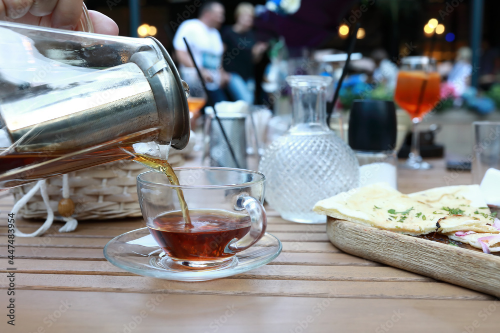 Person pouring black tea into glass