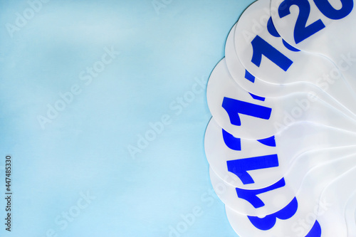 A white plastic fan with blue numbers on it lies on a blue background. Educational concept. background.