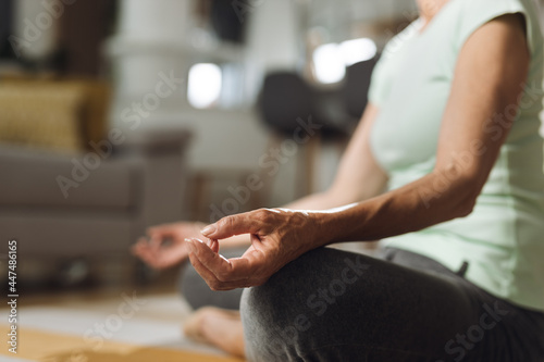 Close up of unrecognizable senior woman practicing Yoga in Lotus position at home