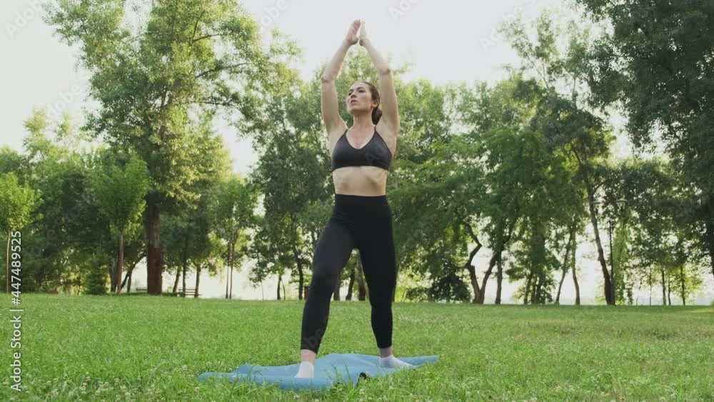 Young fit woman practicing warrior 1 yoga in park at sunset. Pretty girl doing yoga exercises outdoors. Asana Virabhadrasana Young fit woman practicing warrior 1 yoga in park at sunset. Pretty girl doing yoga exercises outdoors. Asana Virabhadrasana