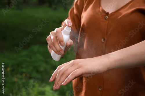 Woman applying insect repellent onto hand in park, closeup. Tick bites prevention