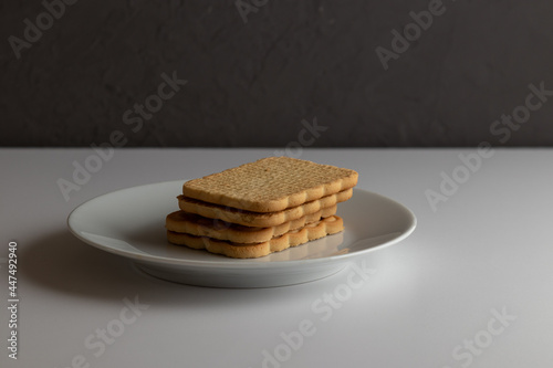 Stack of biscuit on the white plate and white table on black background.