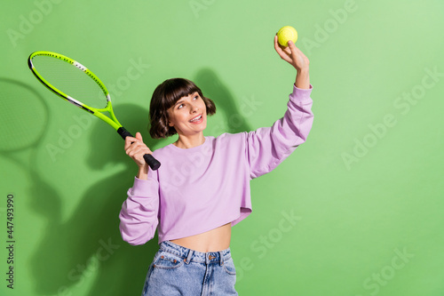 Portrait of attractive cheerful girl playing tennis spending free time isolated over bright green color background © deagreez
