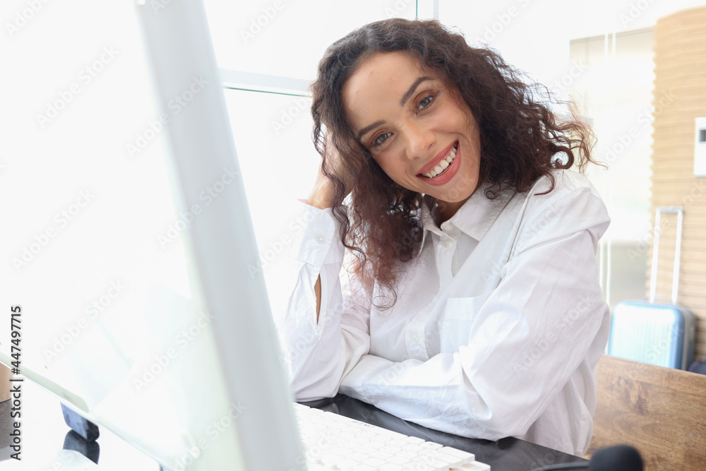 Portrait of happy smiling young beautiful woman with curly hair using desktop computer, female officer staff in casual white shirt sitting at working desk at office workplace. Portrait of happy smiling young beautiful woman with curly hair using desktop computer, female officer staff in casual white shirt sitting at working desk at office workplace.