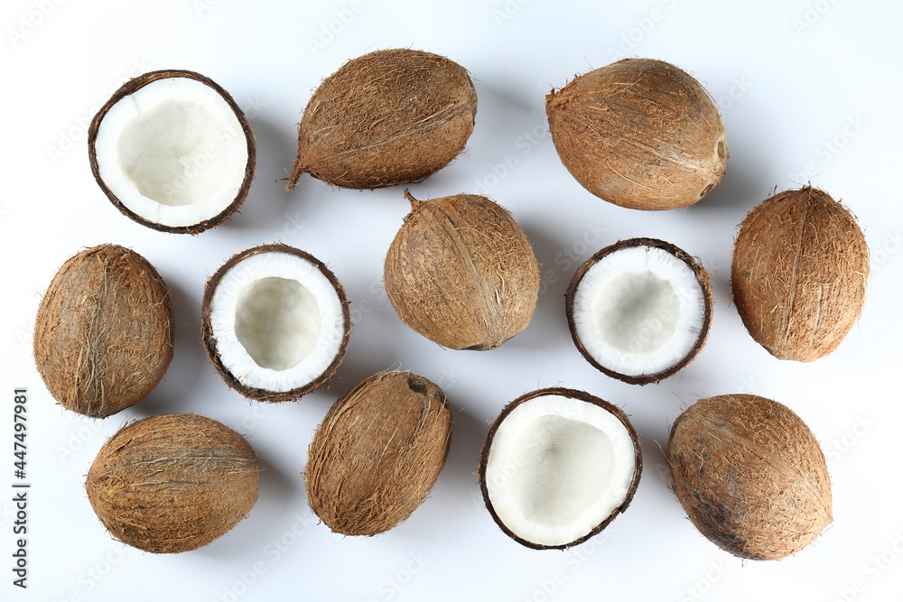Top view shot of coconuts, whole and cracked on halves on paper textured background with a lot of copy space for text. Bacground with raw fruit of tropical palm. Flat lay. Top view shot of coconuts, whole and cracked on halves on paper textured background with a lot of copy space for text. Bacground with raw fruit of tropical palm. Flat lay.