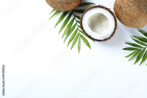 Top view shot of coconuts, whole and cracked on halves on paper textured background with a lot of copy space for text. Bacground with raw fruit of tropical palm. Flat lay.