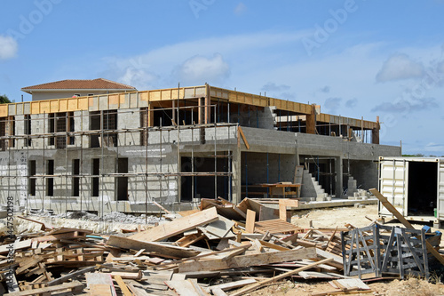 Messy construction site, with scrap wood in the foreground, half finished apartment block building with scaffolding in the background