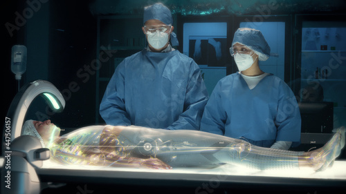 Team of surgeons perform a delicate operation using modern high-tech medical full body surgical augmented reality scanner on female patient laying on futuristic holographic bed showing skeletal system