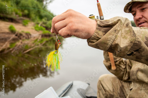 Close-up bait for fish on fishing spinnerbait yellow in the hands of the fisherman. photo
