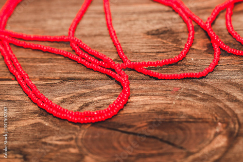 Red beads on a wooden background. Beads and handicrafts for creativity.