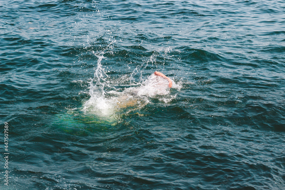 man swimming in the sea, splashing water.