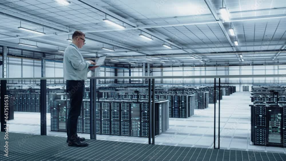 Data Center Engineer Using Laptop Computer. Server Farm Cloud Computing Specialist Facility with Adult Male System Administrator Working with Data Protection Network for Cyber Security. Data Center Engineer Using Laptop Computer. Server Farm Cloud Computing Specialist Facility with Adult Male System Administrator Working with Data Protection Network for Cyber Security.