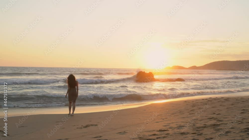 Portrait of a young dark-haired woman walking around the ocean on the background of the sea at sunset.