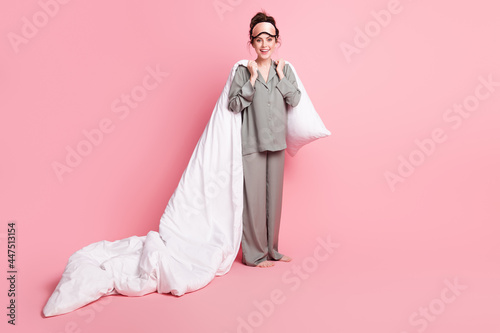 Full length body size photo of girl in pajama keeping pillow white blanket in bedroom isolated on pastel pink color background