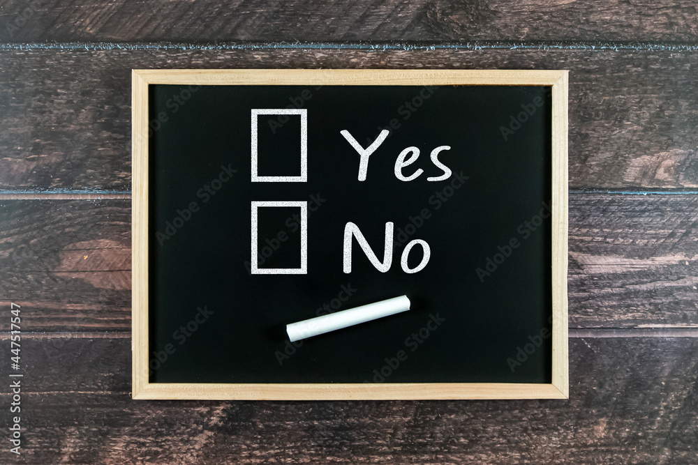 Yes and No written on a blackboard with wooden background.