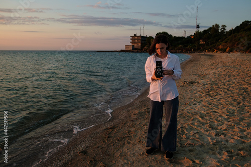 Girl capturing sunrise over the sea on camera. Red dawn on the sea in the morning