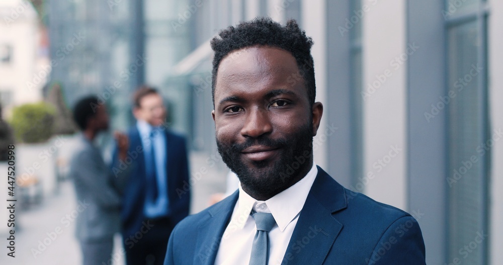 Portrait view of the confident multiracial man wearing formal clothes achieving business success and standing while smiling to the camera