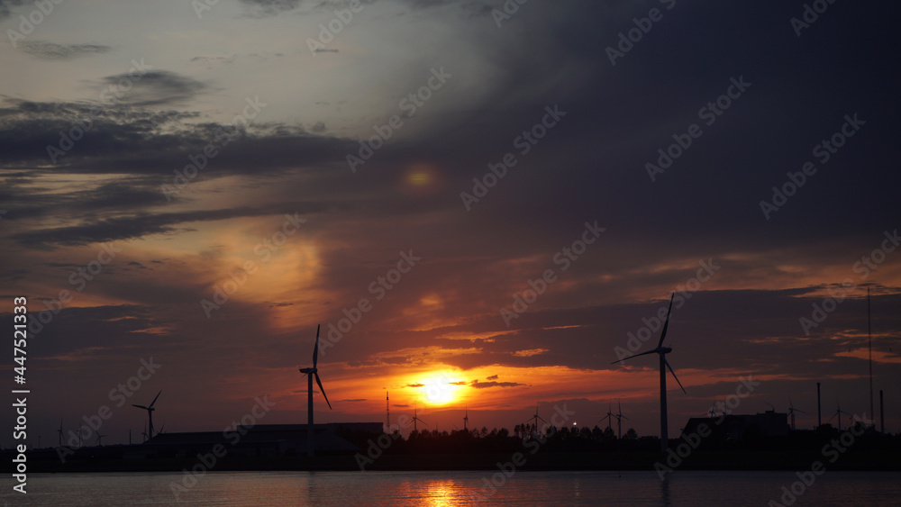 silhouettes of wind turbines and cranes in the harbor at sunset, Hamburg, Germany