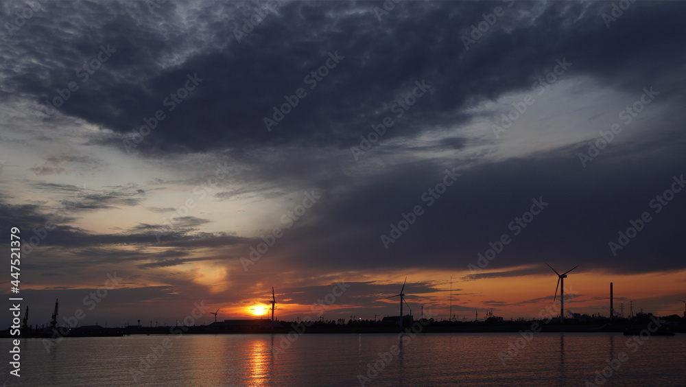 silhouettes of wind turbines and cranes in the harbor at sunset, Hamburg, Germany silhouettes of wind turbines and cranes in the harbor at sunset, Hamburg, Germany