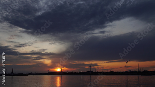 silhouettes of wind turbines and cranes in the harbor at sunset, Hamburg, Germany © Georgios