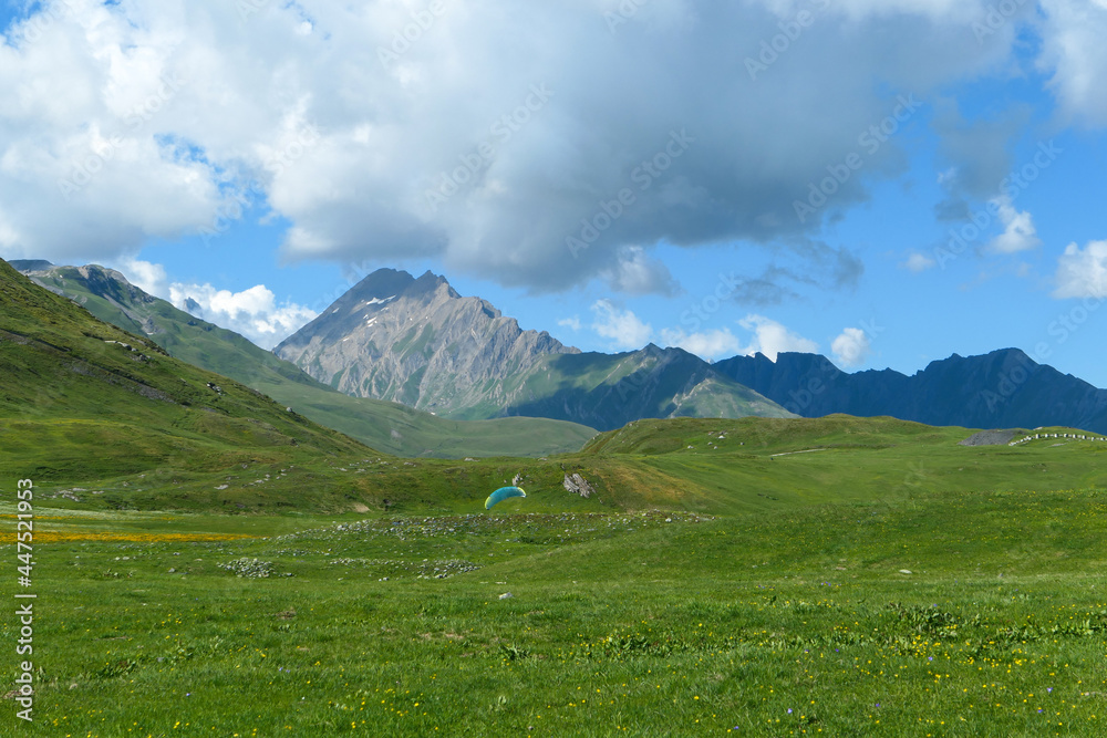 View of the alpine pastures of the Alps in summer. Mountain range in the background with white clouds in a blue sky. Nice holiday landscape.