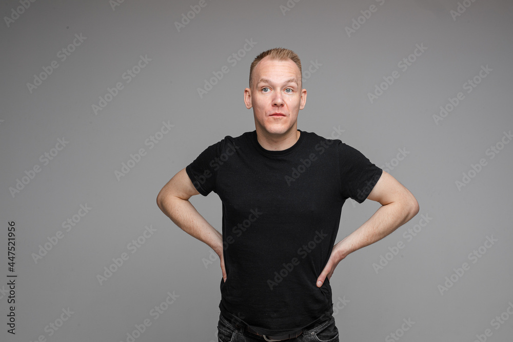 attractive man with short fair hair wearing a black t-shirt and jeans keeps hands on the belt attractive man with short fair hair wearing a black t-shirt and jeans keeps hands on the belt
