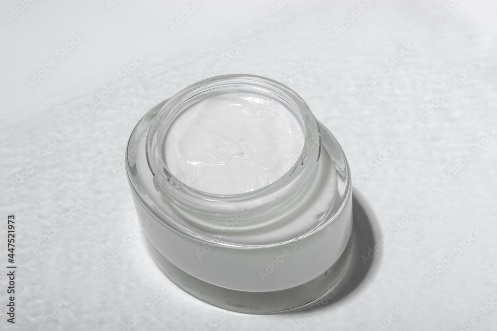 Cosmetic cream or mask in a glass jar with hard shadows from the leaves on a white background. Natural organic care for face and body skin. View from above. Cosmetic cream or mask in a glass jar with hard shadows from the leaves on a white background. Natural organic care for face and body skin. View from above.
